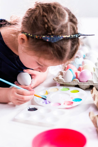 Маленька дівчинка малює ремесло великодні яйця з акриловою фарбою
. - Фото, зображення