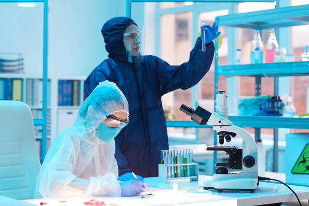 Portrait von zwei Wissenschaftlern in Biohazard-Ausrüstung, die an der Forschung im medizinischen Labor arbeiten, Kopierraum - Foto, Bild
