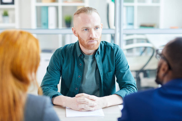 Portrait d'un homme adulte contemporain à l'écoute des gestionnaires des RH lors d'un entretien d'embauche au bureau, espace de copie
 - Photo, image