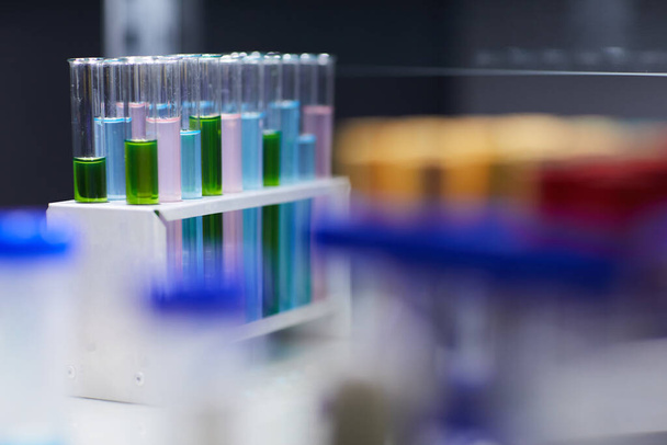 Achtergrondafbeelding close-up van reageerbuizen met gekleurde vloeistof op tafel in laboratorium, kopieerruimte - Foto, afbeelding