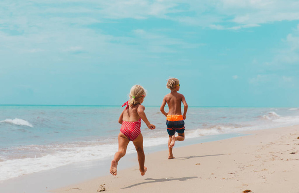 happy boy and girl running on beach - 写真・画像