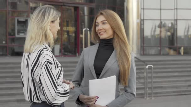 Deux femmes d'affaires scellent l'affaire avec une poignée de main devant un immeuble de bureaux - Séquence, vidéo
