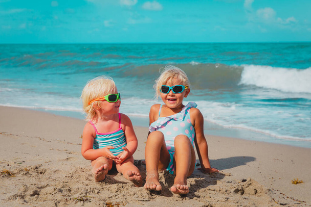 schattig gelukkig kleine meisjes spelen op tropische strand - Foto, afbeelding