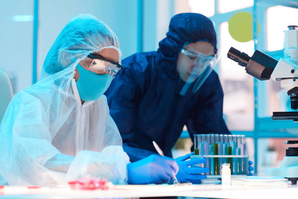 Widok z boku portret dwóch naukowców noszących sprzęt biologiczny, pracujących nad badaniami w laboratorium medycznym, przestrzeń kopiująca - Zdjęcie, obraz