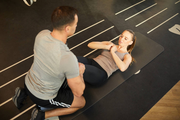 Visão de alto ângulo no treinamento treinador muscular jovem mulher fazendo scrunches no ginásio, espaço de cópia
 - Foto, Imagem
