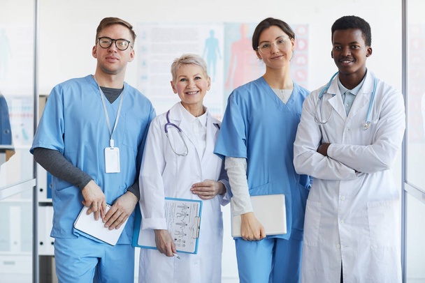 Retrato de cintura hacia arriba de un grupo multiétnico de médicos mirando a la cámara mientras posan juntos en el interior de la clínica
 - Foto, imagen