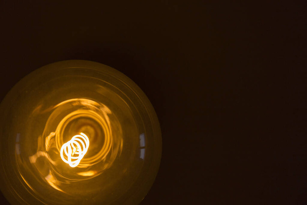 lâmpada amarela com forma espiral em um fundo preto
 - Foto, Imagem