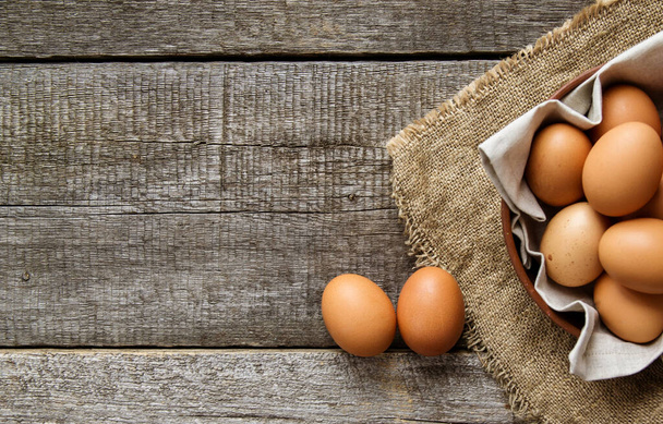 Chicken eggs in a clay plate with a linen napkin and two eggs on burlap. View from above. Copy space. - Zdjęcie, obraz