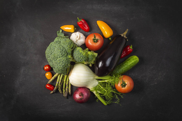 Siyah masada taze organik sebzeler sergileniyor. Domates, biber, brokoli, soğan, sarımsak, salatalık, patlıcan, siyah göz bezelyesi, ekolojik çanta.. - Fotoğraf, Görsel