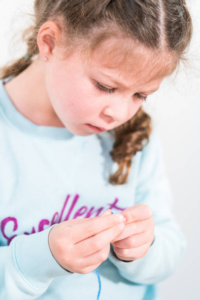 Девочка учится шить с помощью швейного набора для детей. - Фото, изображение