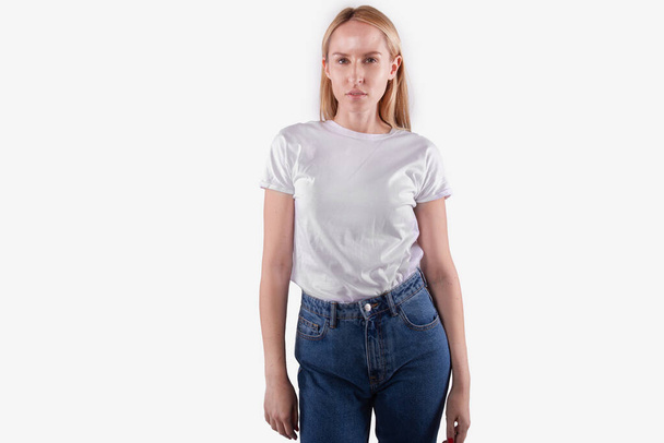 Beautiful young woman in casual wear playfully looks at camera. White background - Zdjęcie, obraz