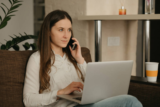Удаленная работа. Белая женщина, работающая дистанционно на ноутбуке. Деловая женщина звонит своему деловому партнеру из дома
. - Фото, изображение