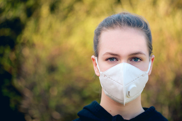 Nuori tyttö, jolla on anti-virus-savusumun naamio kasvoillaan. Hygieniamaskien käyttö vähentää sepelvaltimoviruksen aiheuttaman COVID-19-taudin riskiä; se myös ehkäisee sumuallergioita
 - Valokuva, kuva