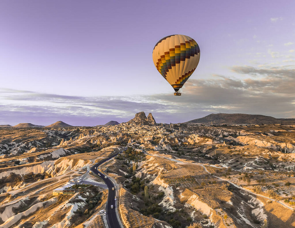 A lone hot air balloon floats high in the sky above the town and roads in Nevsehir - Photo, Image