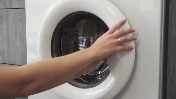 Női kéz házas gyűrűvel GREY SWEATER-t a mosógépbe teszi. Mosógép betöltése. Ruhákat a mosógépbe. Ruha mosógép betöltése. Mosás előkészítése - Felvétel, videó