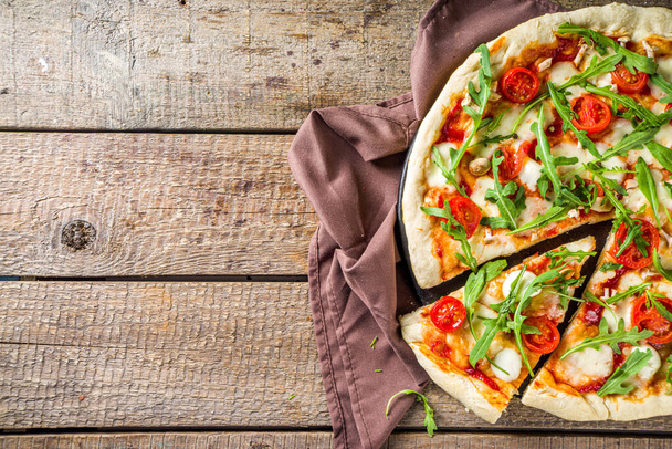Pain plat maison pizza végétalienne. pizza classique italienne avec cerise tomate, fromage mozzarella et roquette fraîche, espace de copie
 - Photo, image
