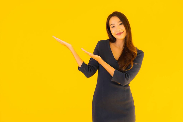 Porträt schöne junge asiatische Frau mit Action auf isoliertem gelben Hintergrund - Foto, Bild