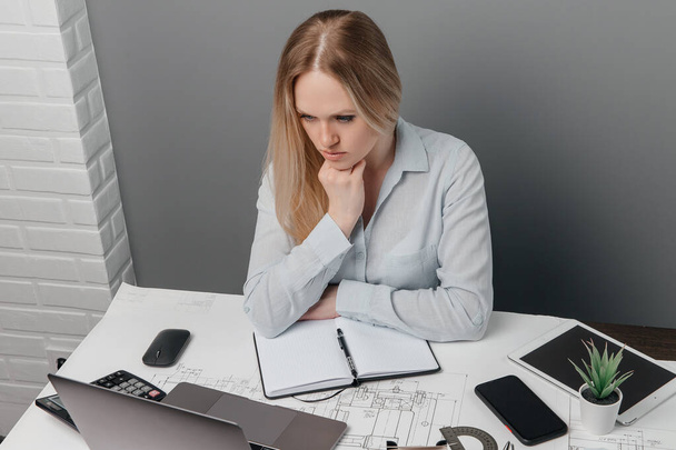 Pensativa dama de negocios se sienta y lee cartas en su computadora portátil en el lugar de trabajo en la oficina
. - Foto, imagen
