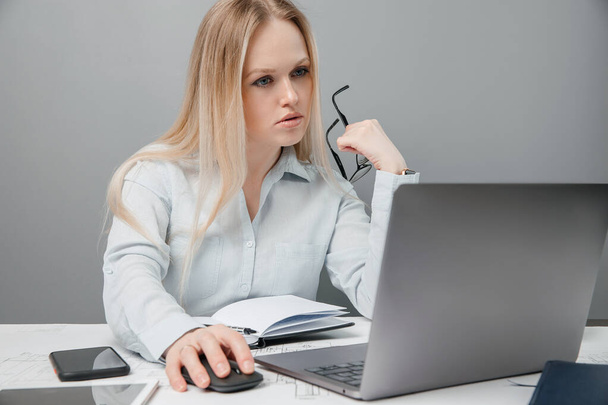 Προσεκτική επιχειρηματίας κυρία κάθεται και διαβάζει γράμματα στο laptop της στο χώρο εργασίας στο γραφείο. - Φωτογραφία, εικόνα