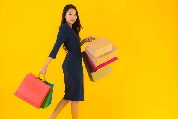 Muotokuva kaunis nuori aasialainen nainen värikäs ostoskassi keltainen eristetty tausta - Valokuva, kuva