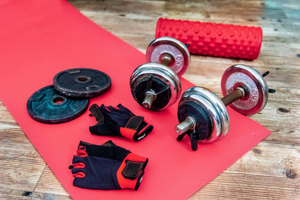 Manubri, guanti da allenamento e rullo di schiuma sul pavimento di un appartamento. Home oggetti di allenamento
 - Foto, immagini