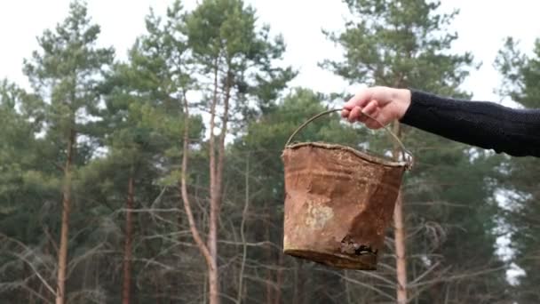 Rozsdás vödör ember kezében erdő háttér Ukrajnában. Szemét az erdőben. Környezetvédelmi katasztrófa. - Felvétel, videó