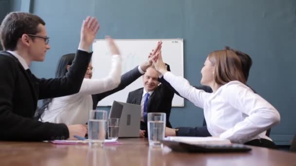 Lächelnde Geschäftsleute, die High-Five machen, während sie mit Kollegen sitzen - Filmmaterial, Video