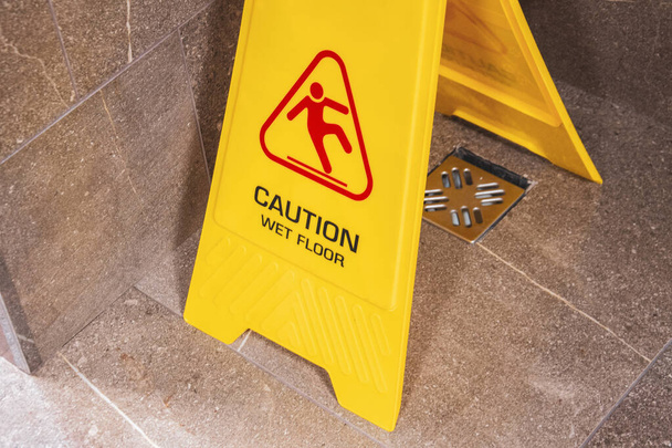 Желтый знак предостерегает от мокрого пола с падающим мужчиной
 - Фото, изображение