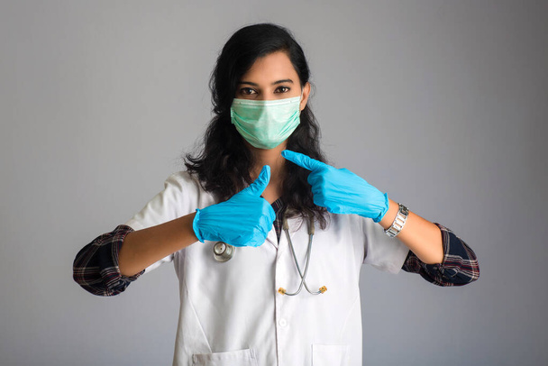 Young woman doctor wearing medical face mask Showing sign. Doctor woman wearing surgical mask for corona virus. - Фото, зображення
