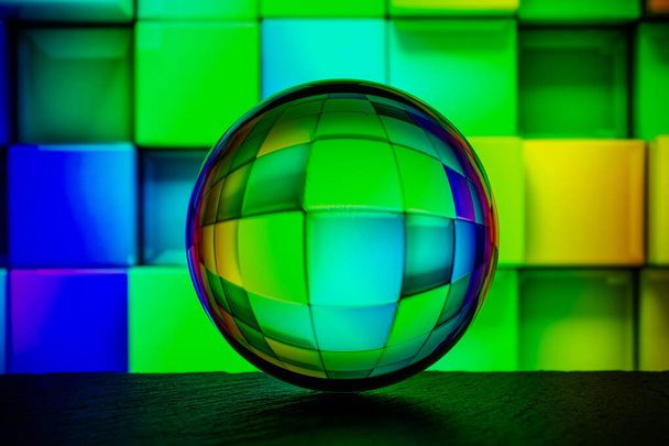 Кришталева скляна куля лежить на поверхні каменю на барвистому абстрактному фоні
.  - Фото, зображення