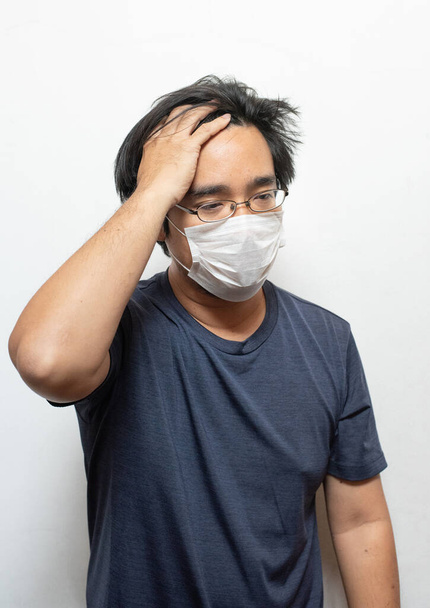 Koronavirüse karşı koruyucu maske takan orta yaşlı Asyalı bir adam. Virüs ve baş ağrısını önlemek için cerrahi maske takan bir adam. Salgın önleme, kişisel hijyen kavramı.. - Fotoğraf, Görsel