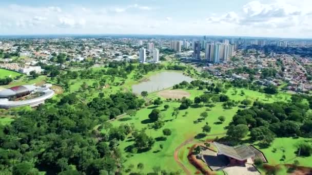 Campo Grande MS, Brezilya 'nın hızlı zoom videosu ve yerli ulusların parkı. Park, göl, yeşil alanlar ve düşük yoğunluklu binaları olan büyük ormanlık bir şehir. Hava görünümü. - Video, Çekim