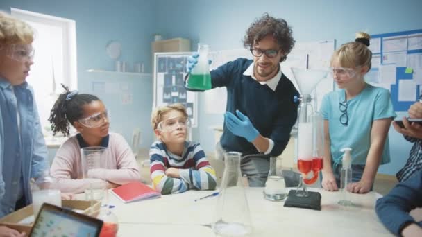 Elementary School Science / Chemistry Classroom: Enthusiastic Teacher Show Funny Chemical Reaction Experiment to Group of Children. Kemikaalien sekoittaminen dekantterissa niin, että ne ampuvat vaahdon (norsun hammastahna
) - Materiaali, video