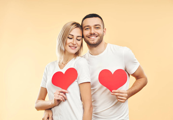 Young couple in love holding big paper hearts in hands over studio background. relationship concept - Foto, Bild