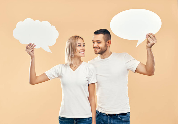 Smiling woman and man holding paper thought bubbles over beige background. relationship concept - Fotó, kép