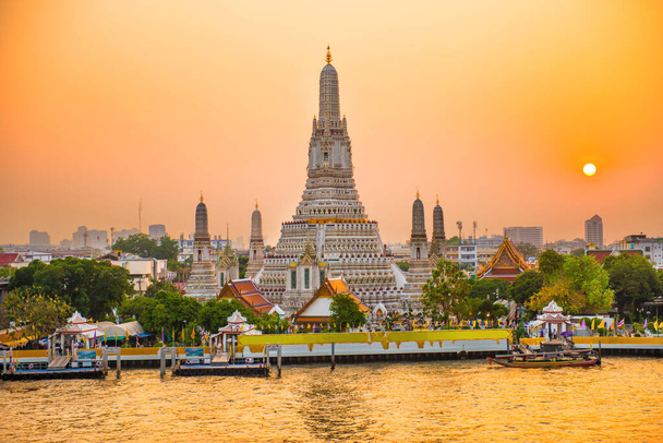 Vista del hermoso Templo del Amanecer o Wat Arun y la orilla oeste de Thonburi del río Chao Phraya al atardecer con sol brillante. Bangkok, Tailandia
 - Foto, Imagen