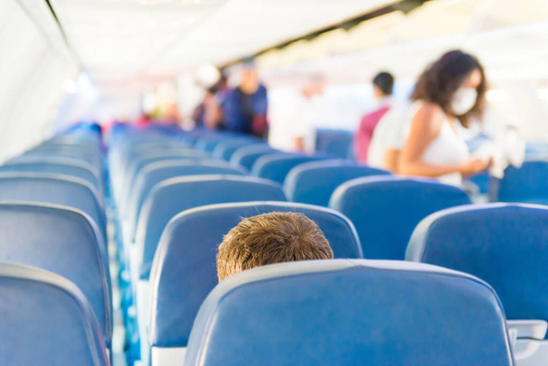 Leerer Flugzeuginnenraum mit wenigen Menschen und Stewardess während der Coronavirus-Pandemie - Foto, Bild