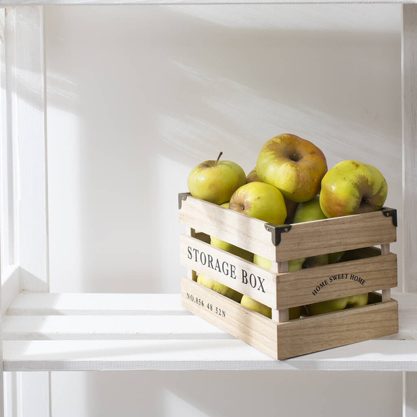 The green apples in the wooden box at the shelf. Concept - Фото, зображення
