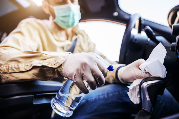 Man in protective suit with mask disinfecting inside car, wipe clean surfaces that are frequently touched, prevent infection of Covid-19 virus coronavirus,contamination of germs or bacteria. Infection prevention and control of viruses.  - Foto, imagen