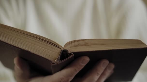 Man leest oud boek, close-up met handen. Zachte focus - Video