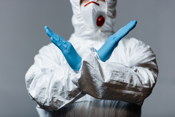 vista recortada del médico maduro en traje de materiales peligrosos, máscara médica y guantes de látex de pie con brazos cruzados aislados en gris
  - Foto, Imagen