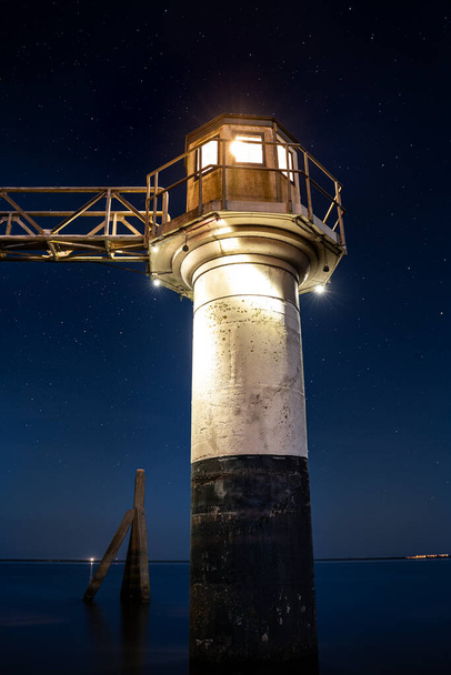 Hafen und historischer nautischer Leuchtturm bei Einbruch der Dunkelheit unter einem klaren blauen Sternenhimmel. Lauwersmeer, Friesland, Niederlande - Foto, Bild