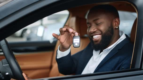 Primer plano hombre de negocios sacudiendo la llave en el coche nuevo. Hombre africano sonriendo en vehículo
 - Imágenes, Vídeo