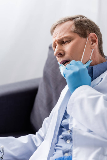 exausto e maduro médico tocando máscara médica
  - Foto, Imagem