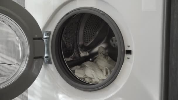 結婚指輪付き男性の手は洗濯機から白い服を取ります。洗濯機を搭載。洗濯機に衣類をロードします。衣類洗濯機をロードします。洗濯の準備 - 映像、動画