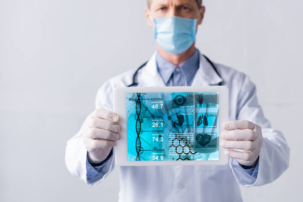 szelektív fókusz orvos orvosi maszk gazdaság digitális tabletta orvosi nyomkövető izolált szürke  - Fotó, kép