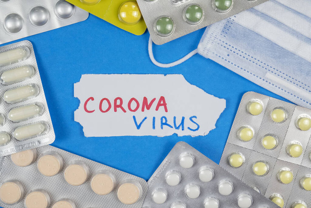 Píldoras, máscara médica y texto CORONAVIRUS sobre fondo rojo Brote de coronavirus chino
. - Foto, imagen