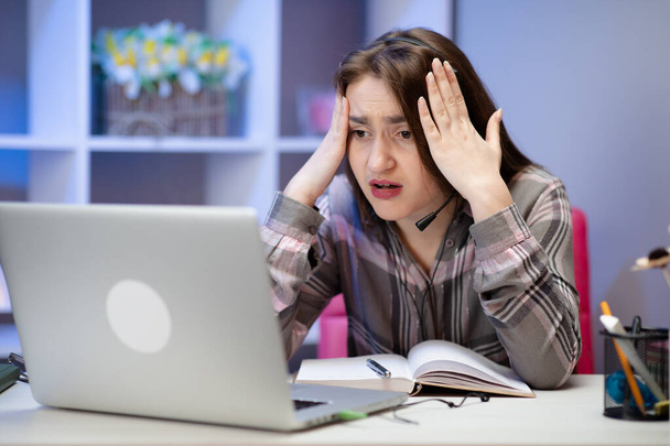 Shocked girl with laptop at home. Cute girl doing homework on computer. Modern online education, communication and technology concept - 写真・画像