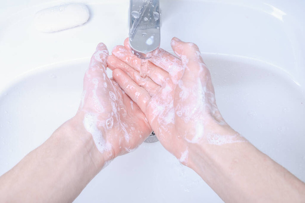 Πλένει τα χέρια στο νεροχύτη τρίβοντας με τον άνθρωπο σαπούνι για τον ιό του στέμματος, πρόληψη COVID-19, υγιεινή για να σταματήσει η εξάπλωση του ιού coronavirus. - Φωτογραφία, εικόνα