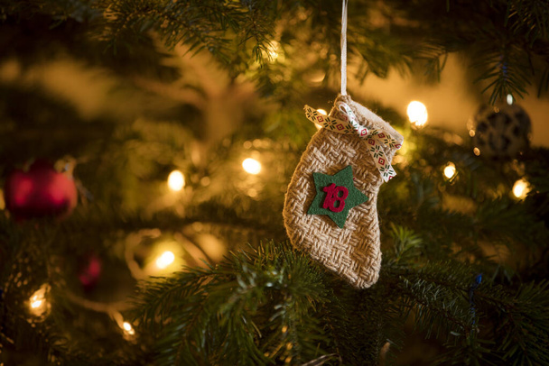 Traditional Advent Calendar Stocking with the date of the 18th of December hanging on a traditional christmas tree. - Photo, Image
